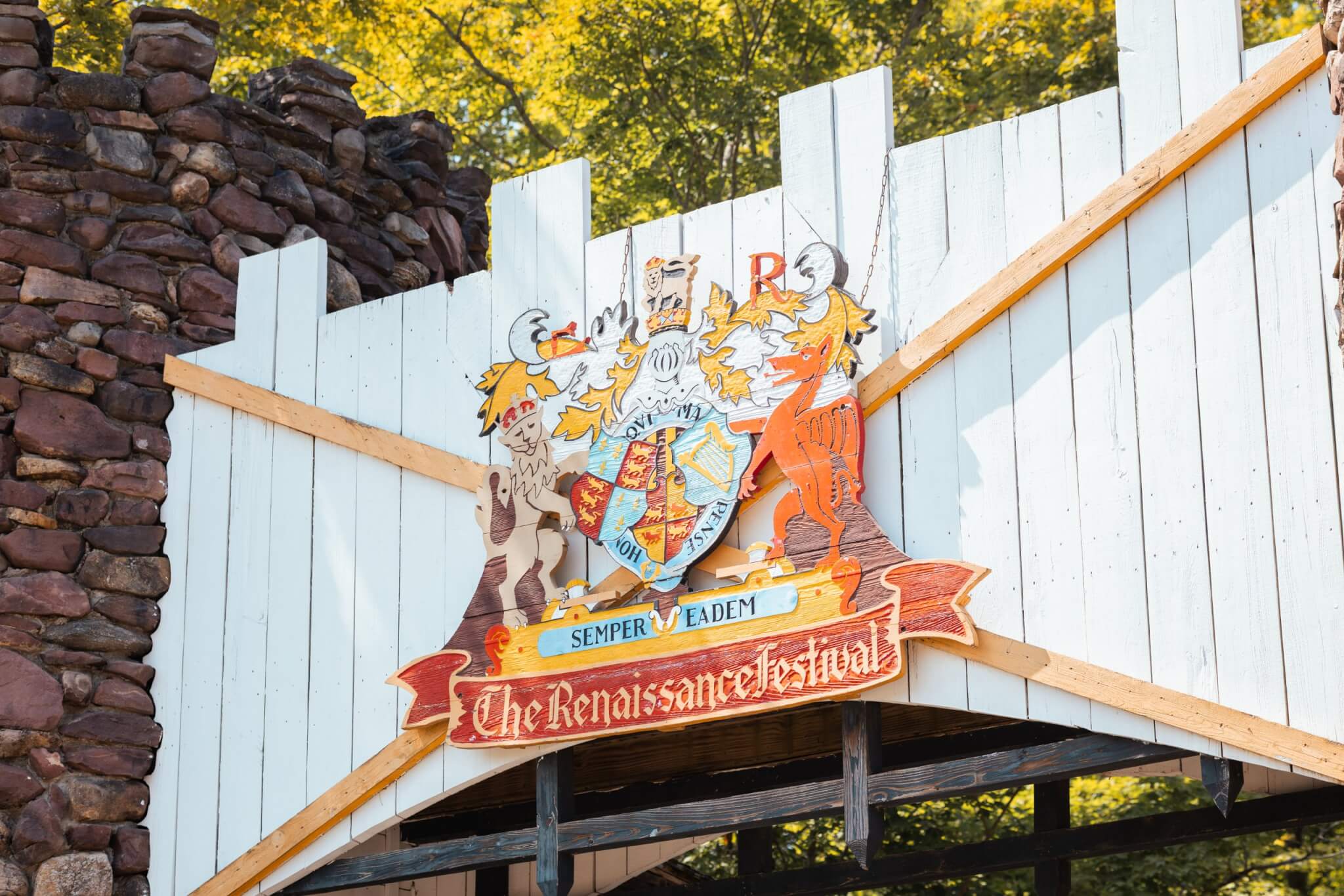 Entrance to the Sterling Renaissance Festival in Sterling, New York, featuring the festival crest mounted above a medieval-style gateway surrounded by stone walls and trees.