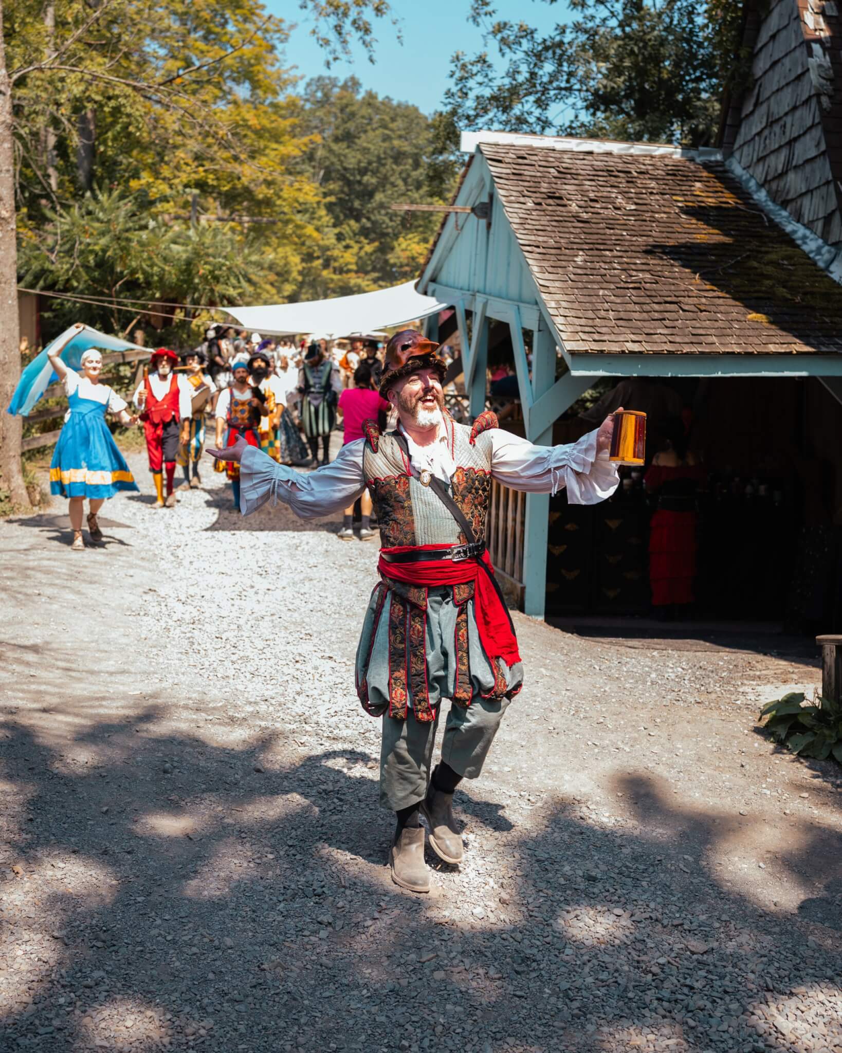 A costumed Renaissance performer entertaining guests along a village pathway during the Sterling Renaissance Festival in the Finger Lakes region of New York.