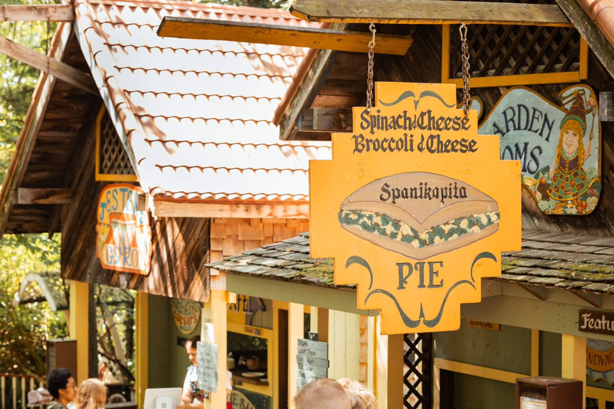 Hand-painted food vendor signs hanging above Renaissance-style market stalls at the Sterling Renaissance Festival in the Finger Lakes region of New York.